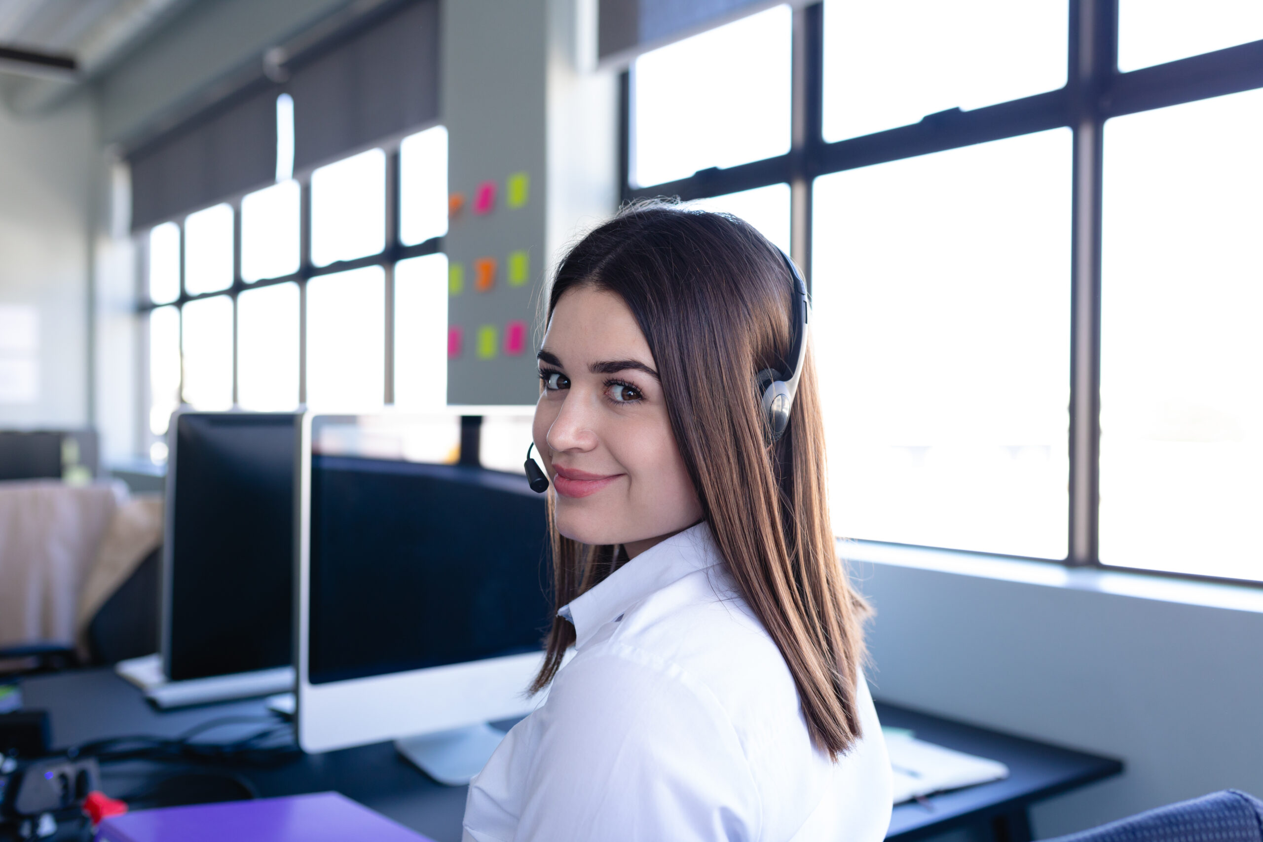 Klantenservice medewerker van Vlucht-Ticket.nl met headset in een moderne kantooromgeving, klaar om reizigers te helpen.