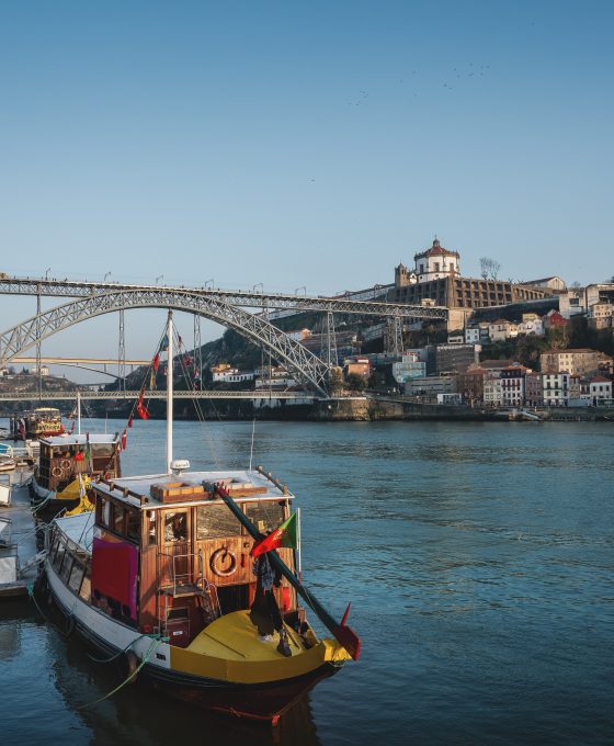 Uitzicht op de Douro-rivier met traditionele boten en de Dom Luís I-brug in Porto.