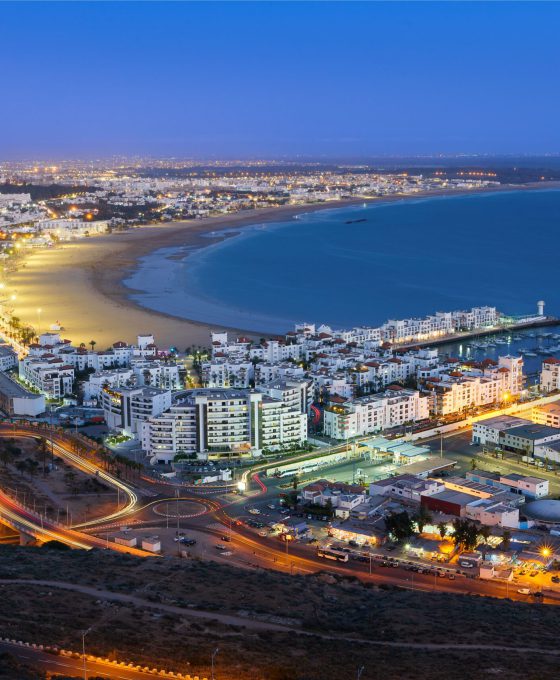 Avondzicht op de kustlijn van Agadir met verlichte straten en het strand.