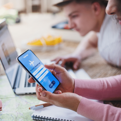 Twee reizigers boeken een last minute vlucht via de app op een smartphone.