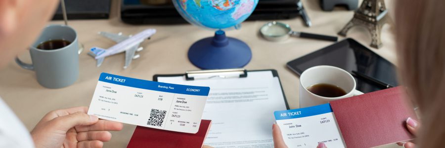 Twee personen houden vliegtickets vast bij een reisbureau met een wereldbol op de achtergrond.